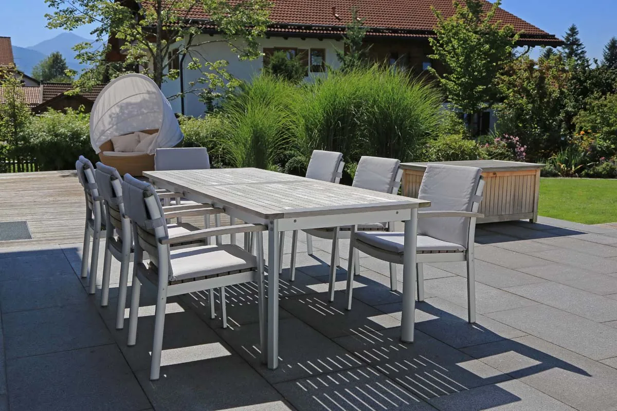 Der lange Esstisch auf der Terrasse, gerahmt von Gräsern