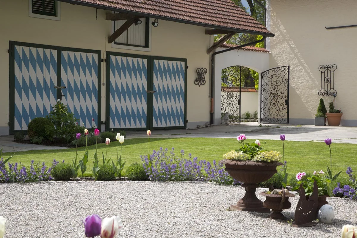 Tulpen und Lavendel im Kiesbeet vor den blau-weißen Hoftoren