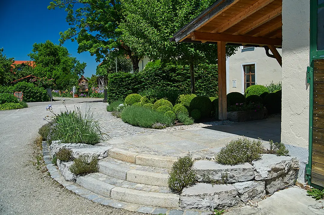 Granitblockstufen führen zum Gartenpavillon, dazwischen Trockenmauer und Formschnitt