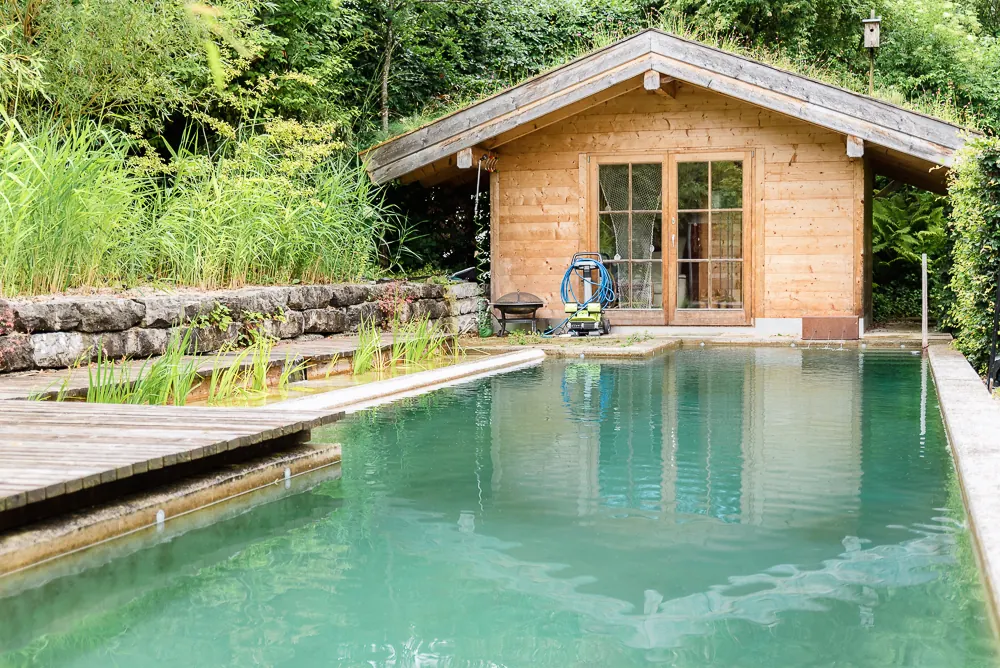 Schwimmteich mit rechteckigem Betonbecken und Holzhaus in Lenggries