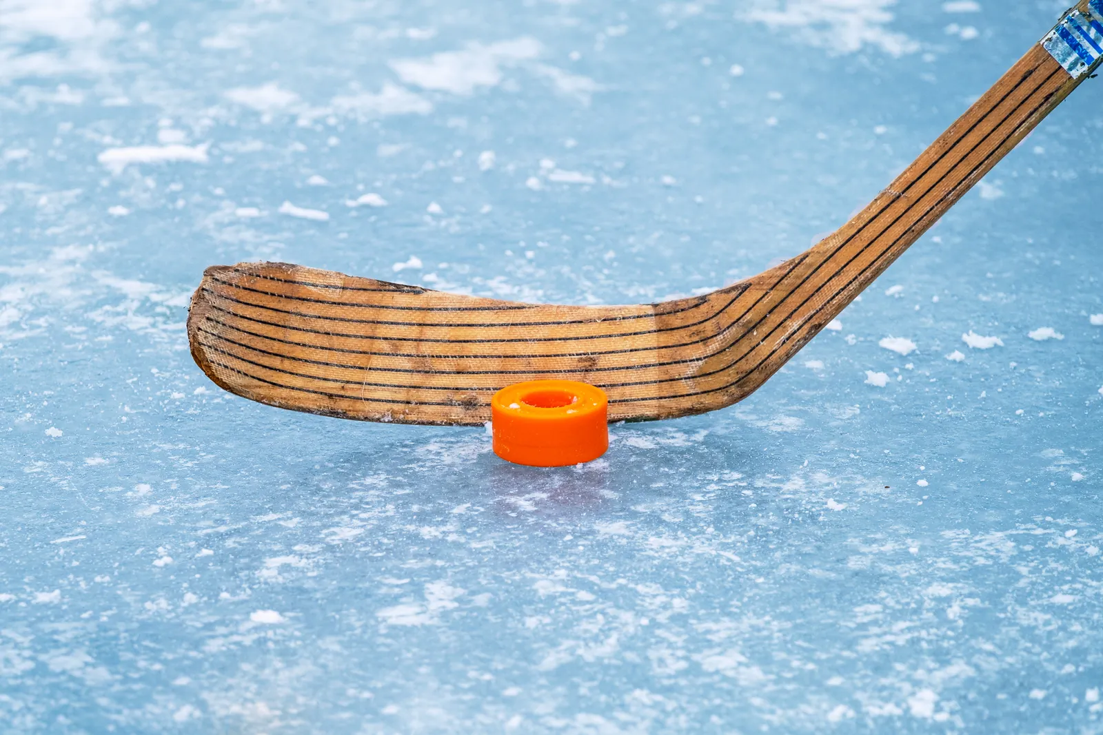 Eishockeyschläger und Puck auf der gefrorenen Fläche eines Schwimmteichs