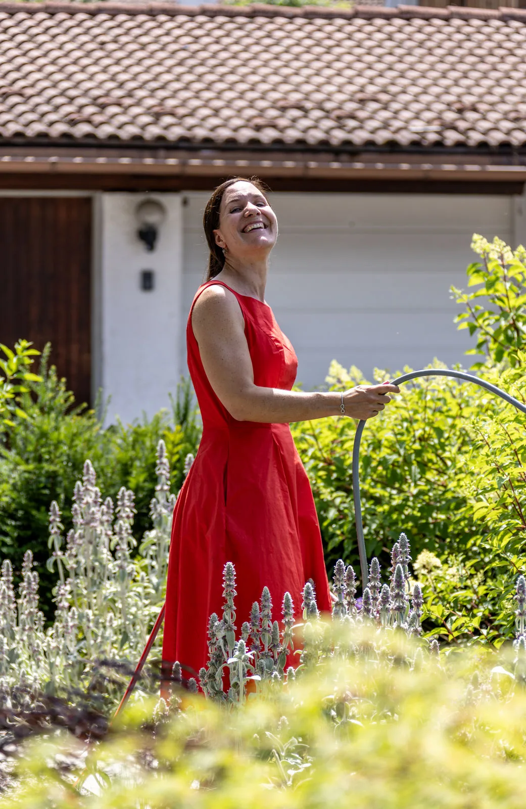 Balbina Fuchs gießt lachend die Staudenbeete im Garten einer Kundin