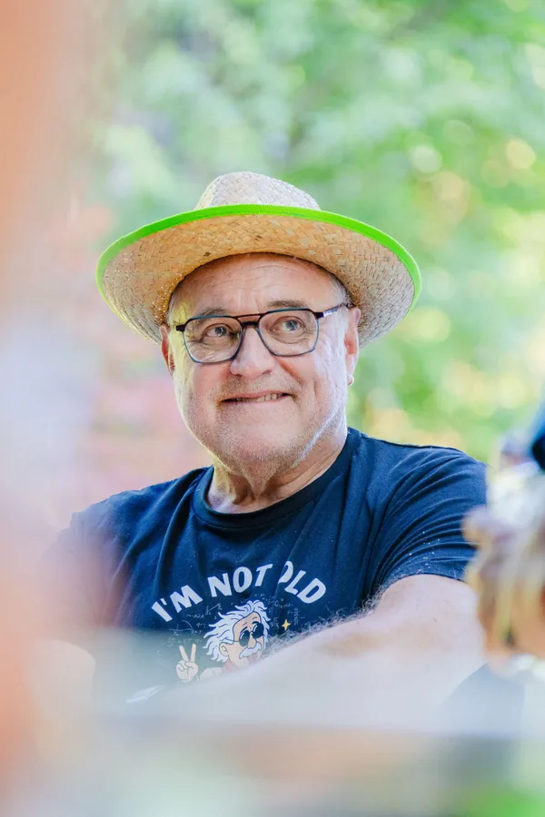 Kollege mit Strohhut und Brille lächelt in die Kamera