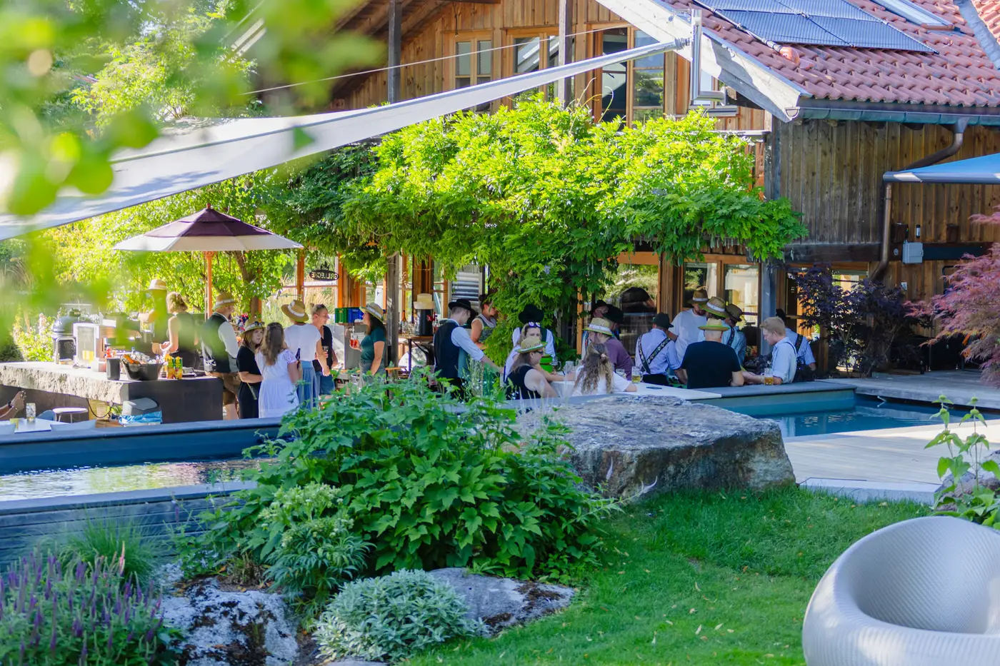 Sommerfest im eigenen Firmengarten: Tische am Living Pool, Sonnensegel über der Terrasse