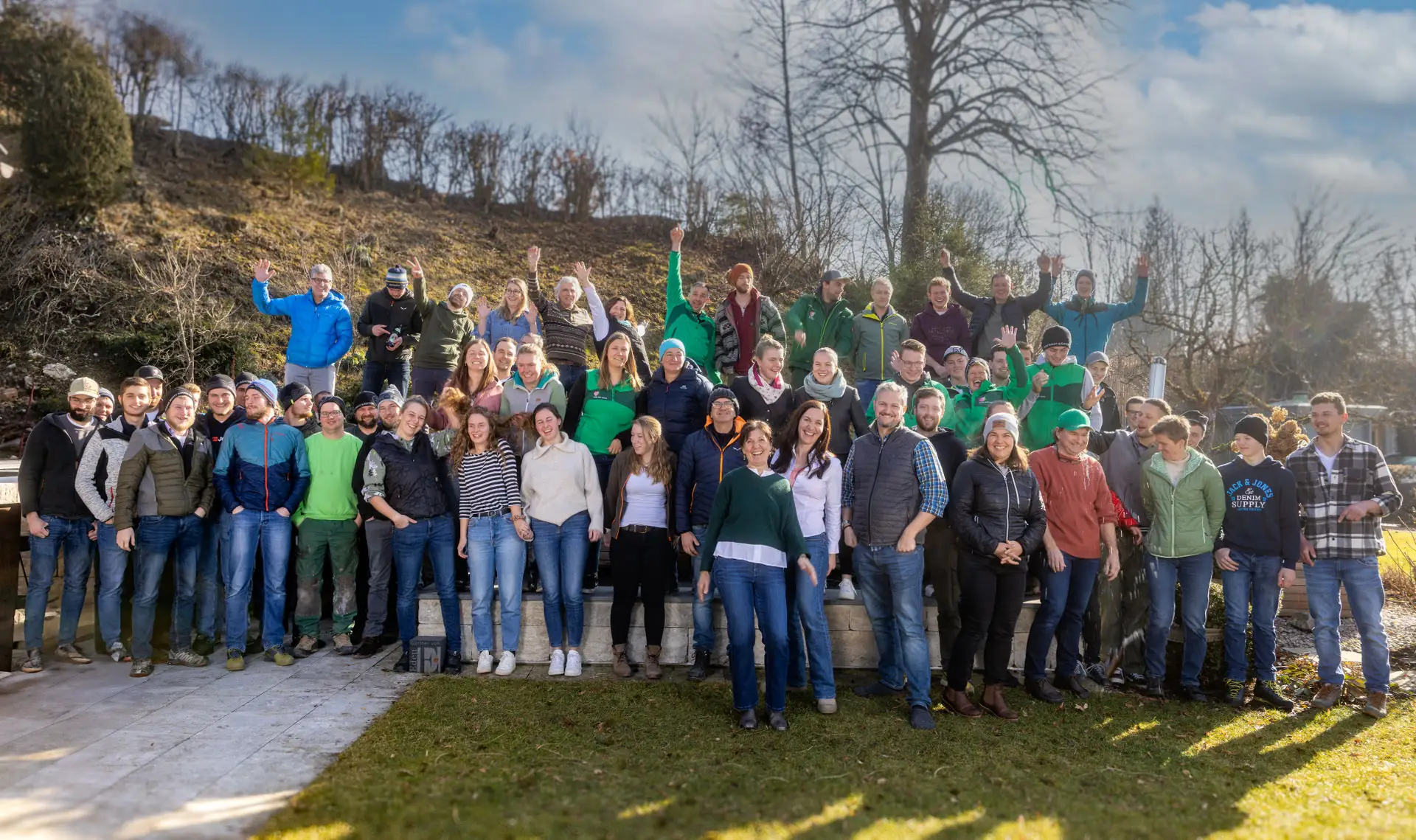 Das Team von Fuchs baut Gärten winkt auf der Wiese am Firmensitz in Schlegldorf