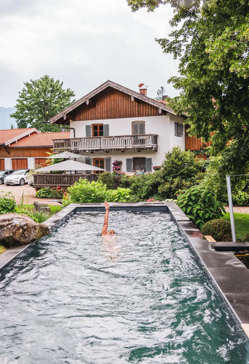 Living Pool am Bürogebäude von Fuchs baut Gärten in Lenggries, jemand schwimmt darin