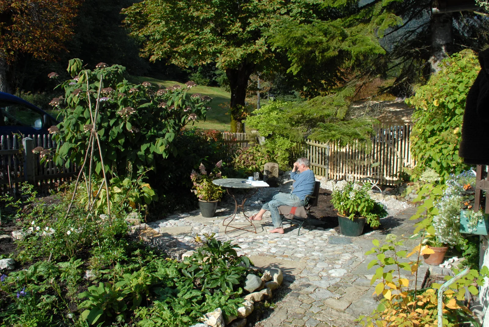 Naturnaher Garten mit Kiesweg, dichter Bepflanzung und Holzzaun